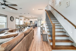 A spacious living area with a wooden staircase, a dining area, and a kitchen in the background. - Walk to Beach! 'ocean's Paradise' w/ Patio (Port St. Joe)