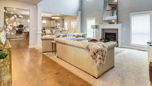 A spacious living room with a large beige sectional sofa, a fireplace, and a kitchen in the background. - 9 Mi to Mystic Falls Tours! Spacious Group Getaway (Covington)