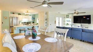 A spacious living area with a dining table, chairs, a blue sofa, and a ceiling fan. - 1/2 Mi to Beach! Rural Home w/ Deck in Port St Joe (Port St. Joe)