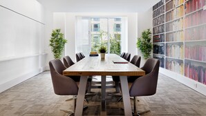 A conference room with a long wooden table, brown leather chairs, a potted plant, and a bookshelf filled with books. - For Students Only Ensuites in Southampton (Southampton)