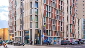 En bygning med flere etager og moderne arkitektur, med en facade i et gittermønster, store vinduer og en markant indgang.