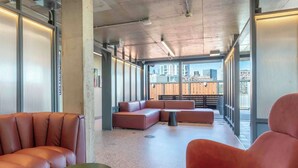 Et moderne loungeområde med læderpolstrede møbler, et lille bord og store vinduer med udsigt over byen.