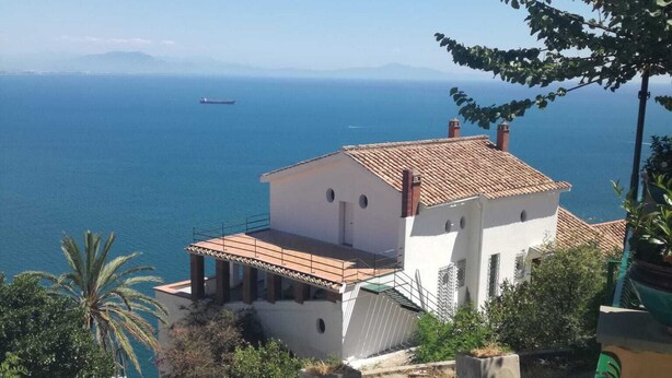 Ein Küstenhaus mit Ziegeldach, einem Balkon und Blick auf das Meer.