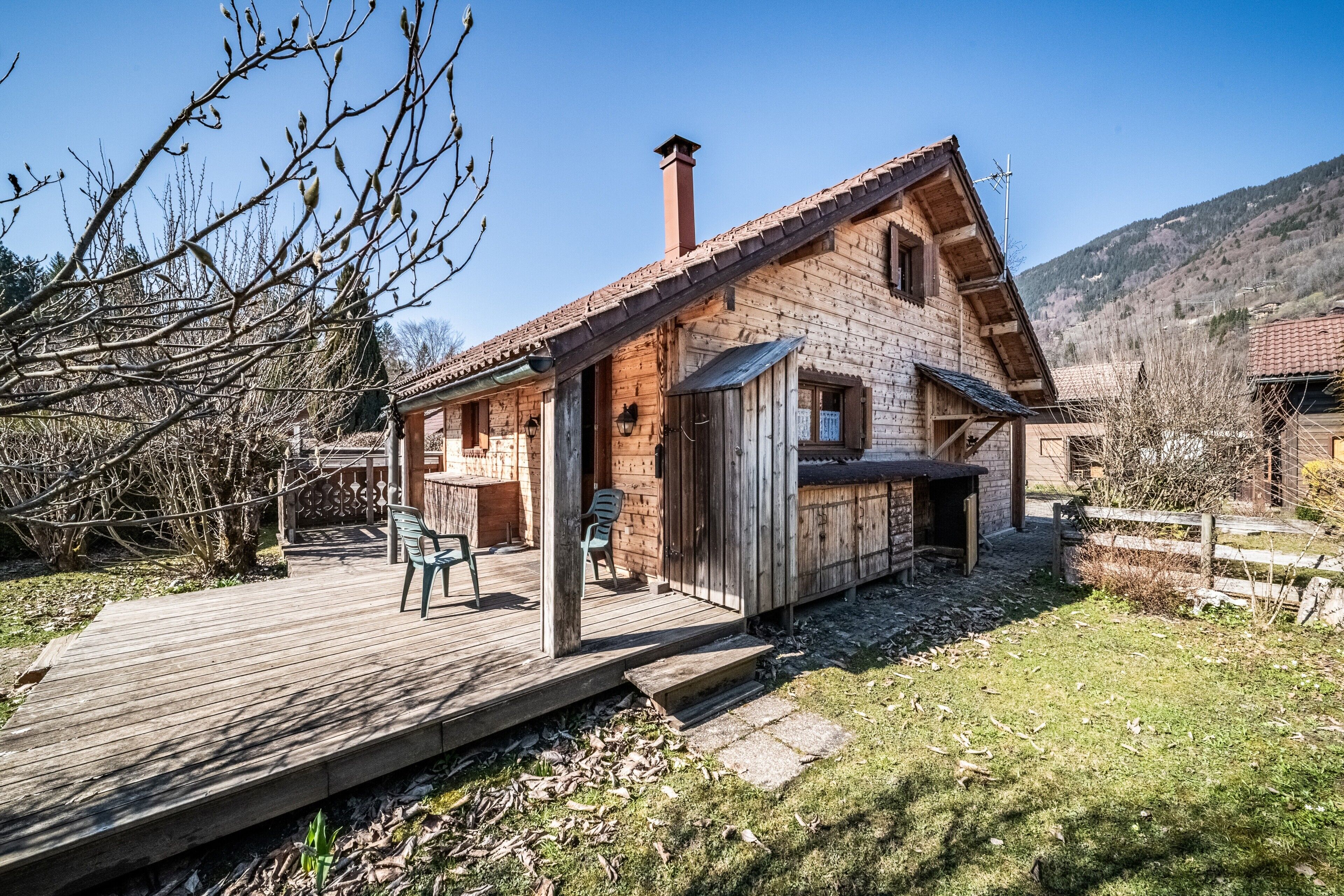 Una casa di legno con veranda, un camino e montagne sullo sfondo.