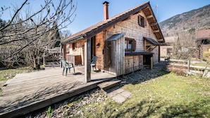 A wooden house with a deck, a chimney, and a mountainous backdrop. - Chalet “8p Comfort – Le Gaby” with Mountain View and Wi-Fi (Verchaix)