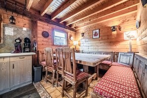 Interior de una cabaña de madera con una mesa de comedor, sillas y bancos.