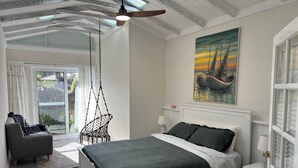 Una camera da letto con un letto, una sedia a dondolo, un quadro e una finestra con tende.
