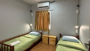 A room with two single beds, a ceiling fan, an air conditioning unit, and a small wooden nightstand. - OYO 91278 5minutes Lodge (Kota Kinabalu)