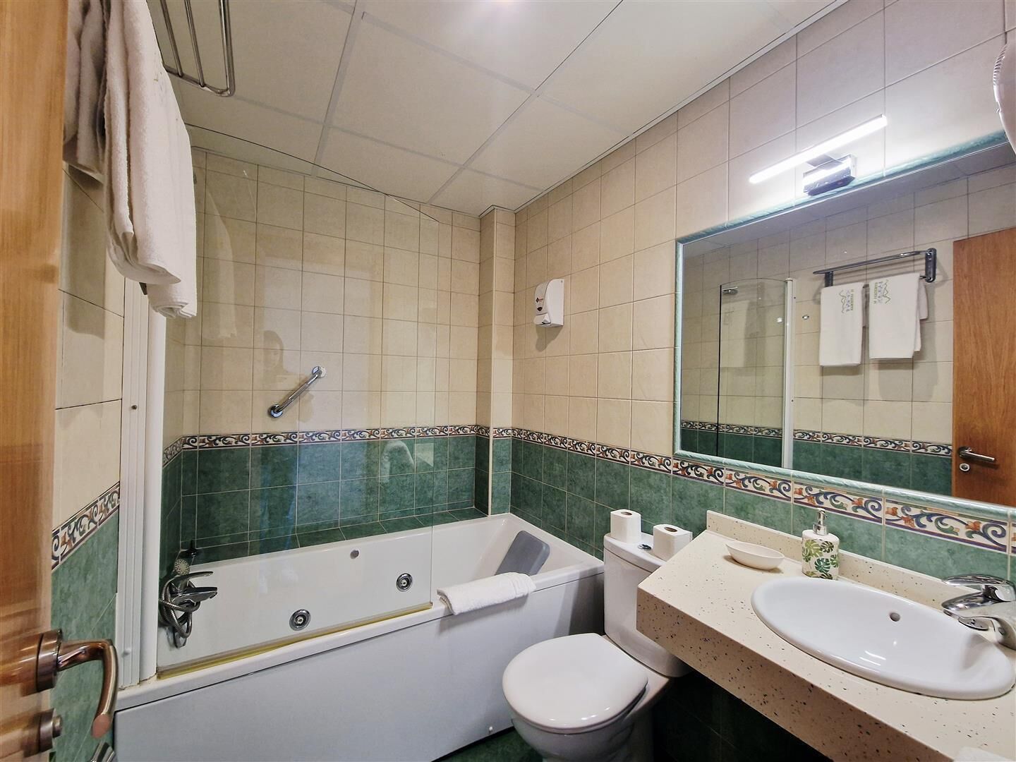 Een badkamer met een bad, toilet, wastafel en een grote spiegel.