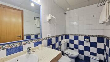 Une salle de bain avec un lavabo, des toilettes et une douche.