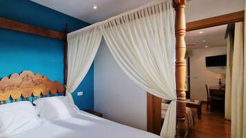 A bedroom with a four-poster bed, a blue accent wall, and a wooden floor.