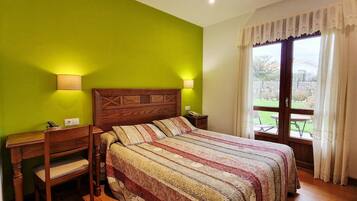 Una camera da letto con un letto in legno, due lampade sui comodini, una scrivania e vista all'esterno tramite una porta in vetro.