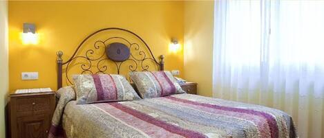 Uma cama com colcha estampada, cabeceira com design circular e duas luminárias fixadas na parede.