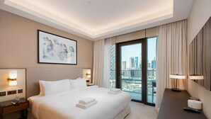 Ein modernes Hotelzimmer mit einem großen Bett, einem Schreibtisch und Blick auf die Stadt durch das Fenster.