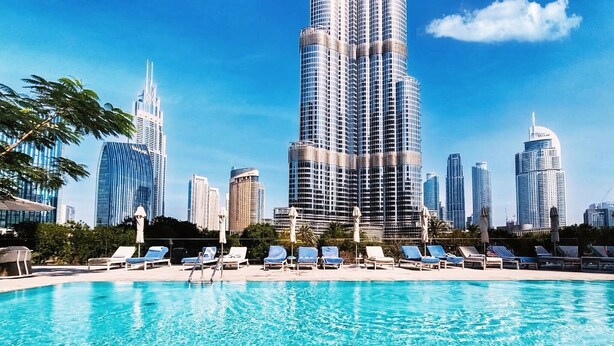 Ein Swimmingpool mit Liegestühlen und einer Stadtkulisse im Hintergrund.