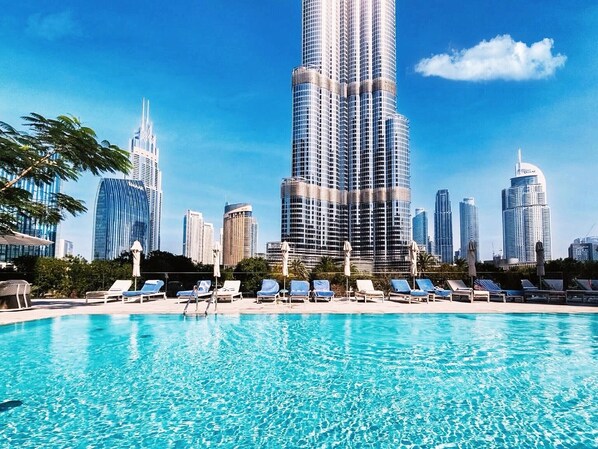 Ein Swimmingpool mit Liegestühlen und einer Stadtkulisse im Hintergrund.