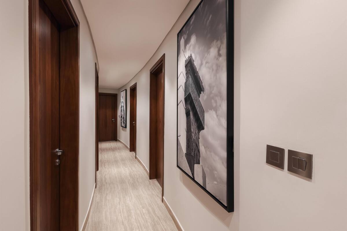 A hallway with wooden doors, a framed picture on the wall, and light-colored flooring.