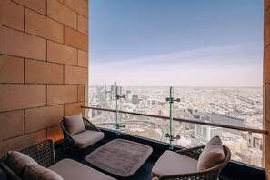 A balcony with wicker furniture and a city view. - Radisson Collection Residences, Riyadh (Riyadh)