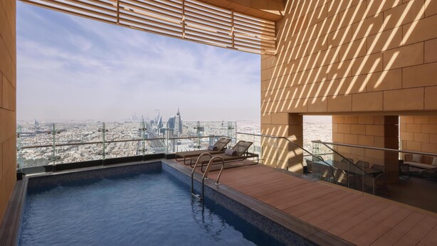 Una piscina sul tetto con vista sulla città, un pontile in legno e poltrone relax.