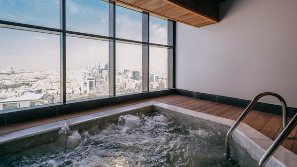 Un bain à remous avec vue sur la ville, de grandes fenêtres et un plancher en bois.