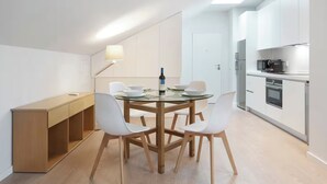 Una cuina moderna amb armaris blancs, forn integrat i microones.