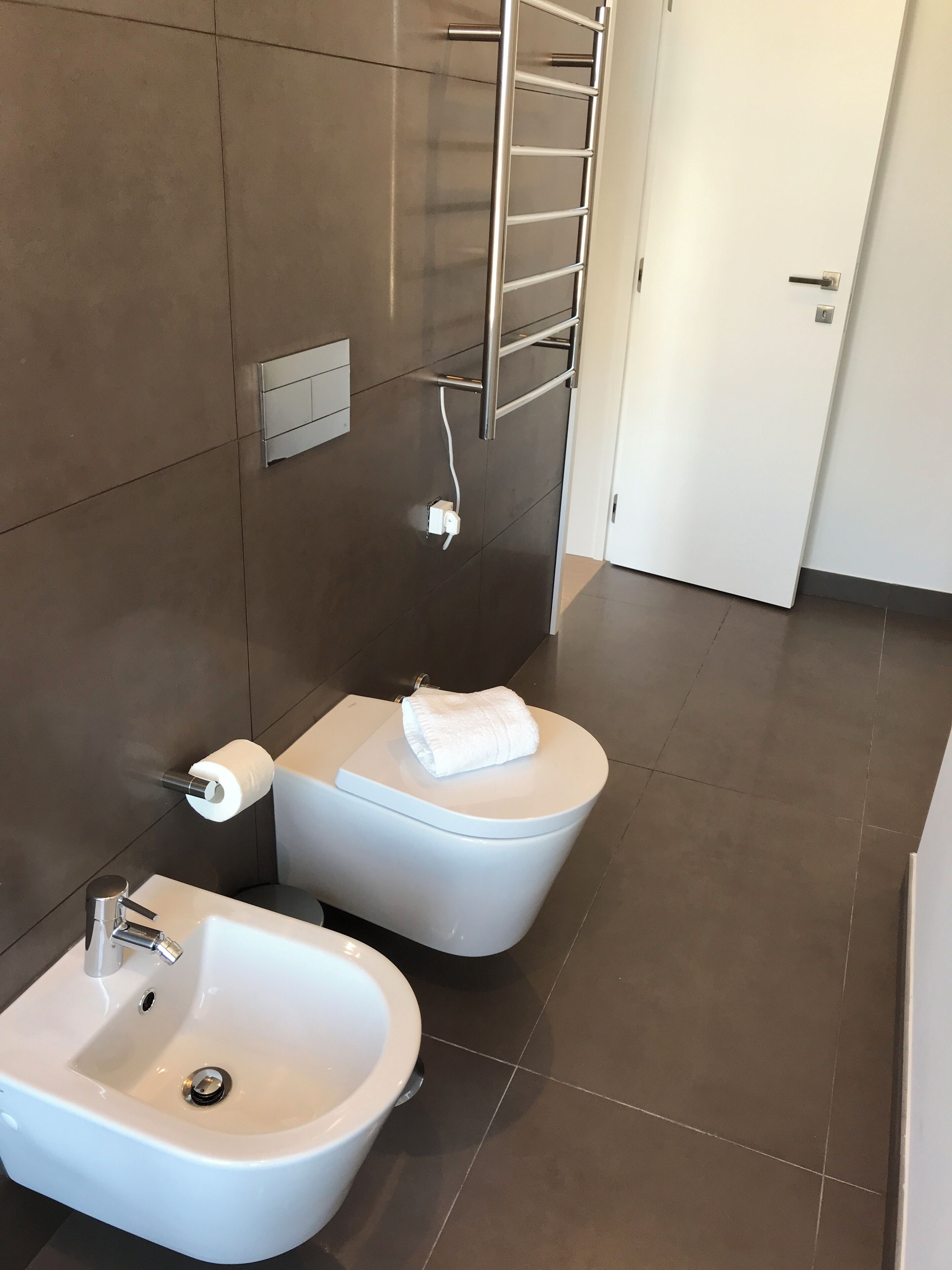 Un bagno moderno con bidet, water e lavandino.