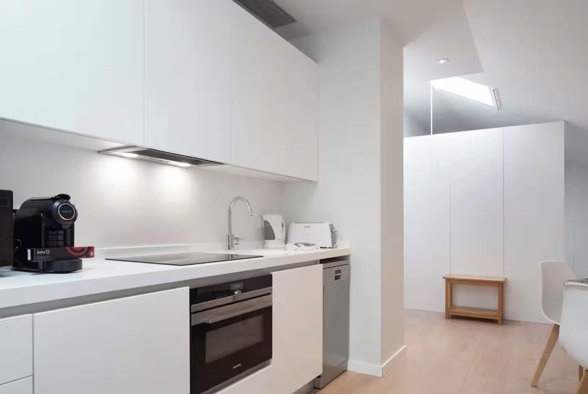 A modern kitchen with white cabinetry, a coffee maker, a toaster, and a dishwasher.