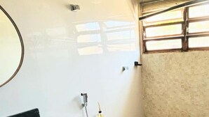 A compact bathroom with a white toilet, a black sink, and a shower area. - Tortuga Suite: comfortable and functional, close to the beach. (Guarujá)