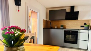 A modern kitchen with a built-in oven, a black range hood, and a wooden countertop.