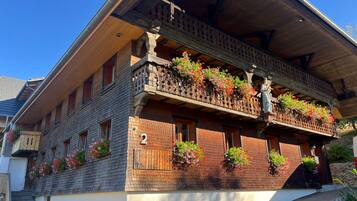 Ein traditionelles Chalet mit Holzfassade, mehreren Balkonen mit Blumenkästen und der deutlich sichtbaren Nummer 2 am Gebäude.