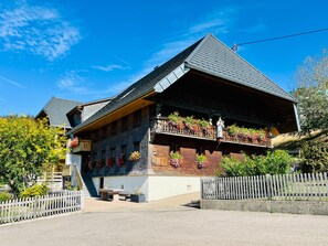 A traditional chalet with a sloped roof, wooden balconies with flower boxes, and a white facade.