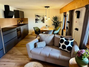 A modern living space with a sofa, dining table, chairs, and a kitchen area.