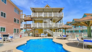 A multi-story hotel with a swimming pool, outdoor seating, and a lifeguard stand. - Beachgate Condo Suites And Hotel 237+239 2 Bedroom Condo (Port Aransas)