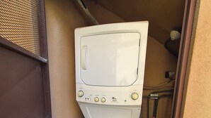 A compact laundry area with a washing machine and dryer stacked vertically. - Beautiful home in gated community on private beach and Golf course in Costa Rica (Tambor)