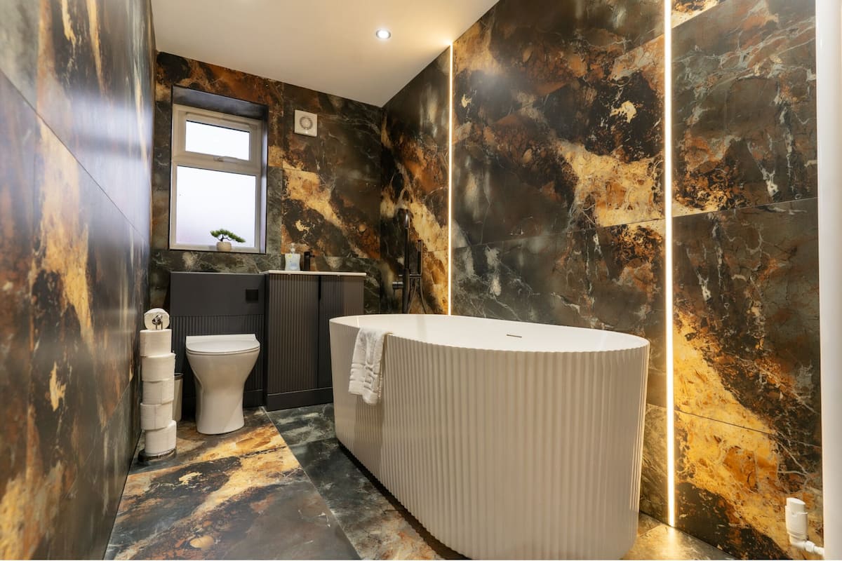 Een moderne badkamer met een vrijstaand bad, een toilet en een wastafel met spiegel.