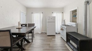 Una cocina compacta con una mesa de comedor, sillas, un refrigerador, una estufa y un microondas.