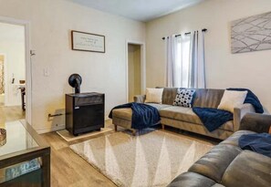 Un salon comprenant un canapé, une table basse, une cheminée et une porte donnant sur une autre pièce.