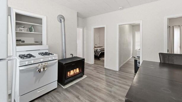 Una cocina moderna con estufa blanca, estufa de leña y una zona de comedor con mesa oscura.