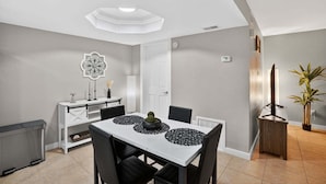 Uma sala de jantar com uma mesa branca, cadeiras pretas e um centro de mesa decorativo.