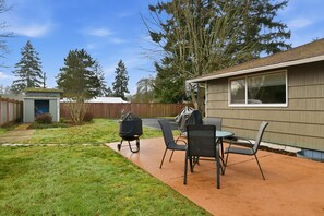 A backyard with a patio, a barbecue grill, and a covered table with chairs. - Hoops & Hygge Private Sport Court Retreat 3 Bedroom Home (Lakewood)