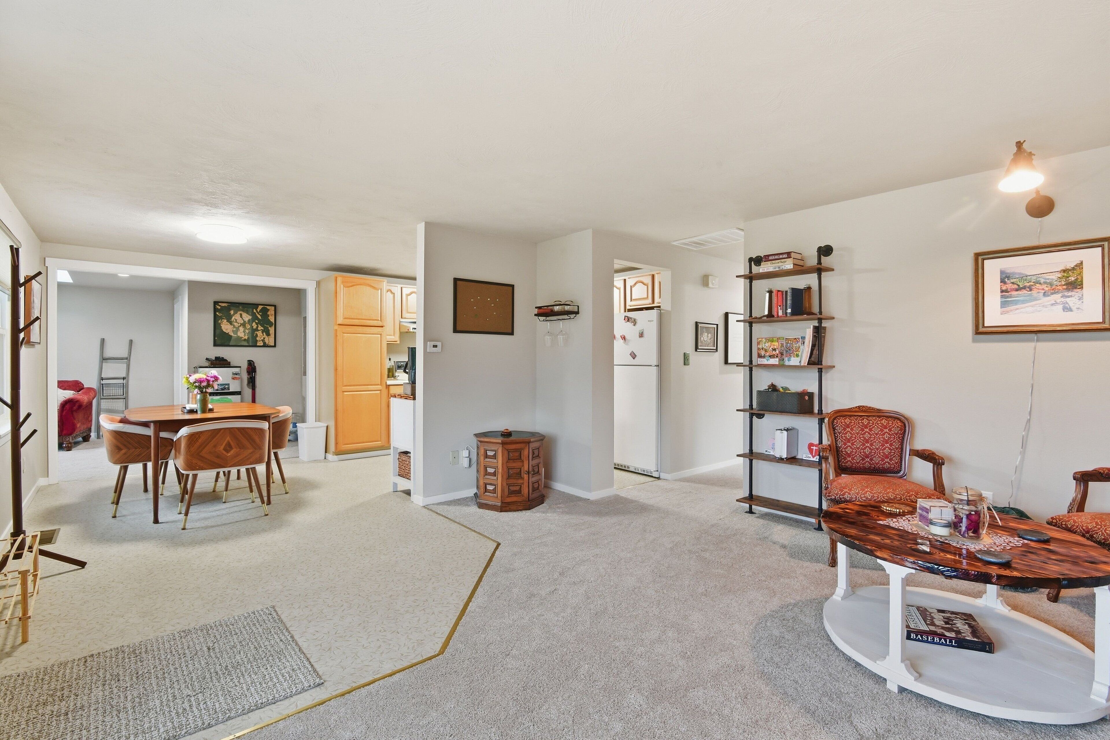 A living room with a dining area, a bookshelf, and a coffee table.