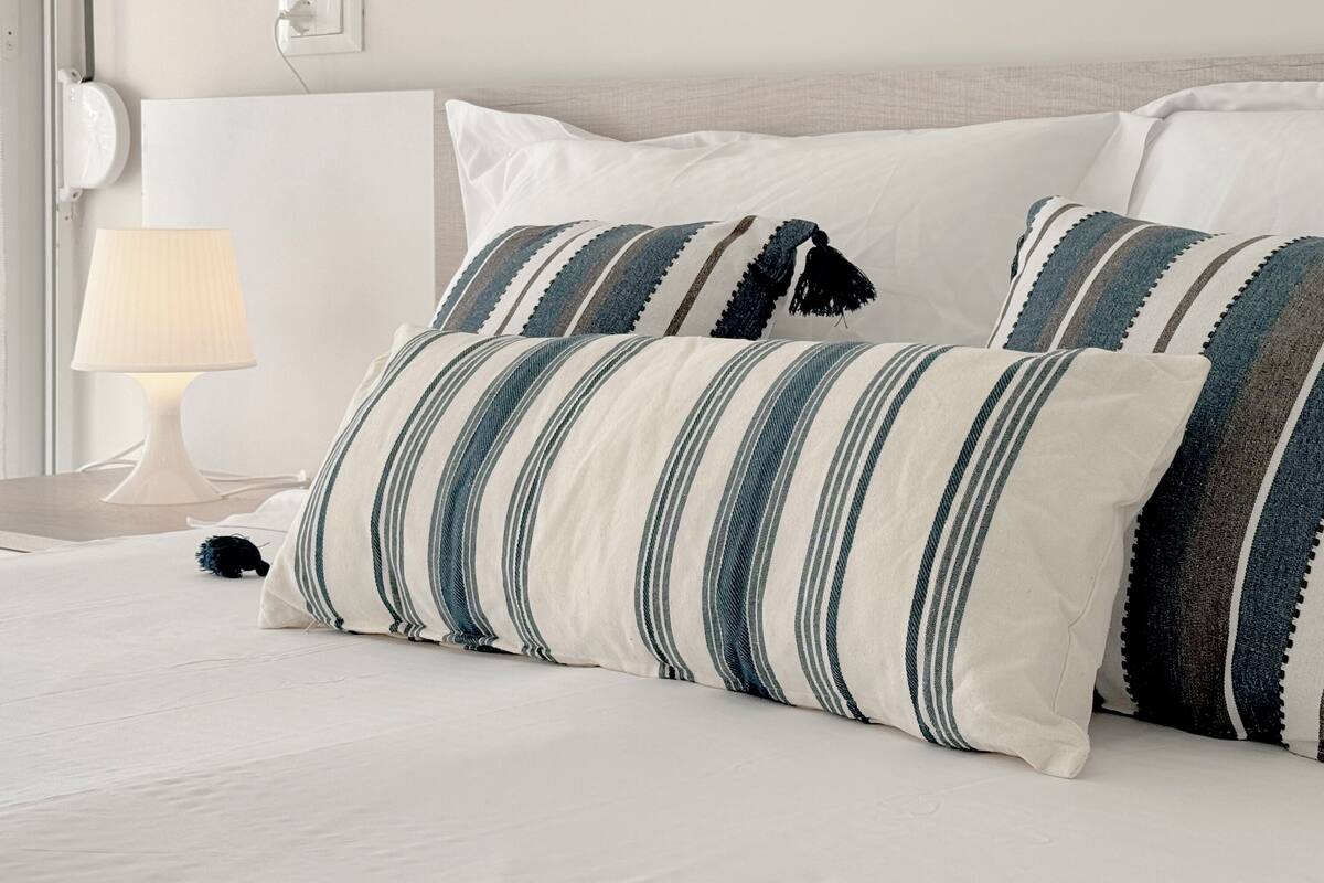 A neatly made bed with striped pillows and a bedside lamp.