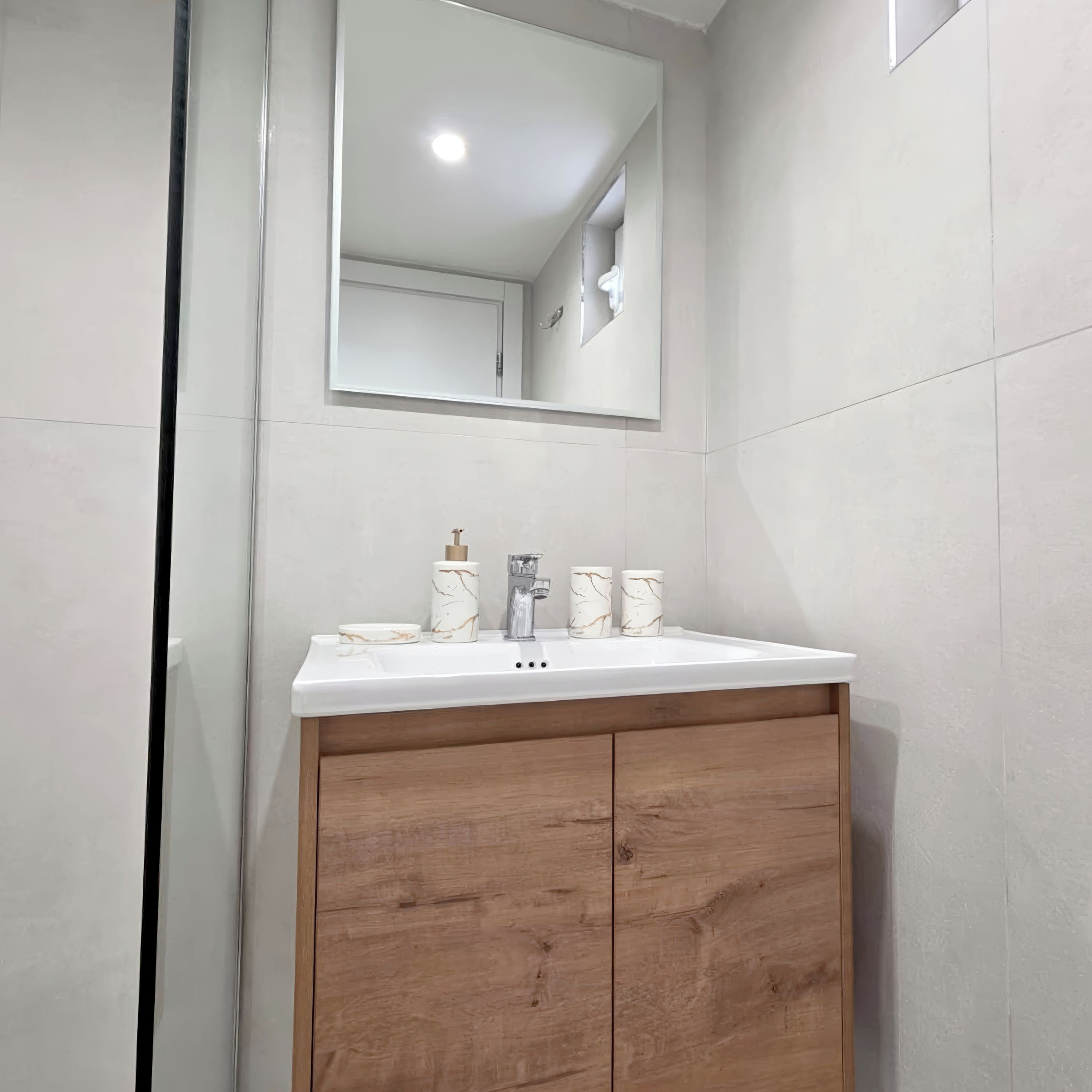 A bathroom with a white sink, wooden cabinet, and a mirror.