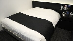 A hotel room with a bed, a nightstand, and a control panel with amenities. - Utility Hotel Cooju (Kawagoe)