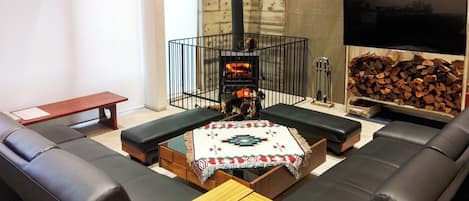 Una sala de estar moderna con chimenea, sofás de cuero negro, una mesa de centro de madera y un televisor.