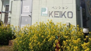 Rakennuksessa on kyltti, jossa lukee ”KEIKO Pension”, ja erillinen kyltti, joka osoittaa parkkipaikan.