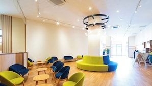 A spacious lobby with a central seating area, a reception desk, and a modern ceiling design.
