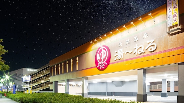 A building with a large illuminated sign, multiple levels, and a parking area.
