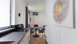 Una cocina moderna con comedor, que cuenta con un amplio ventanal, una mesa de comedor con sillas y una obra de arte contemporánea en la pared.