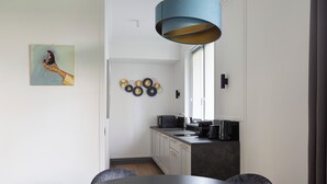 Una cocina moderna con armarios blancos, una encimera oscura y una lámpara colgante azul.